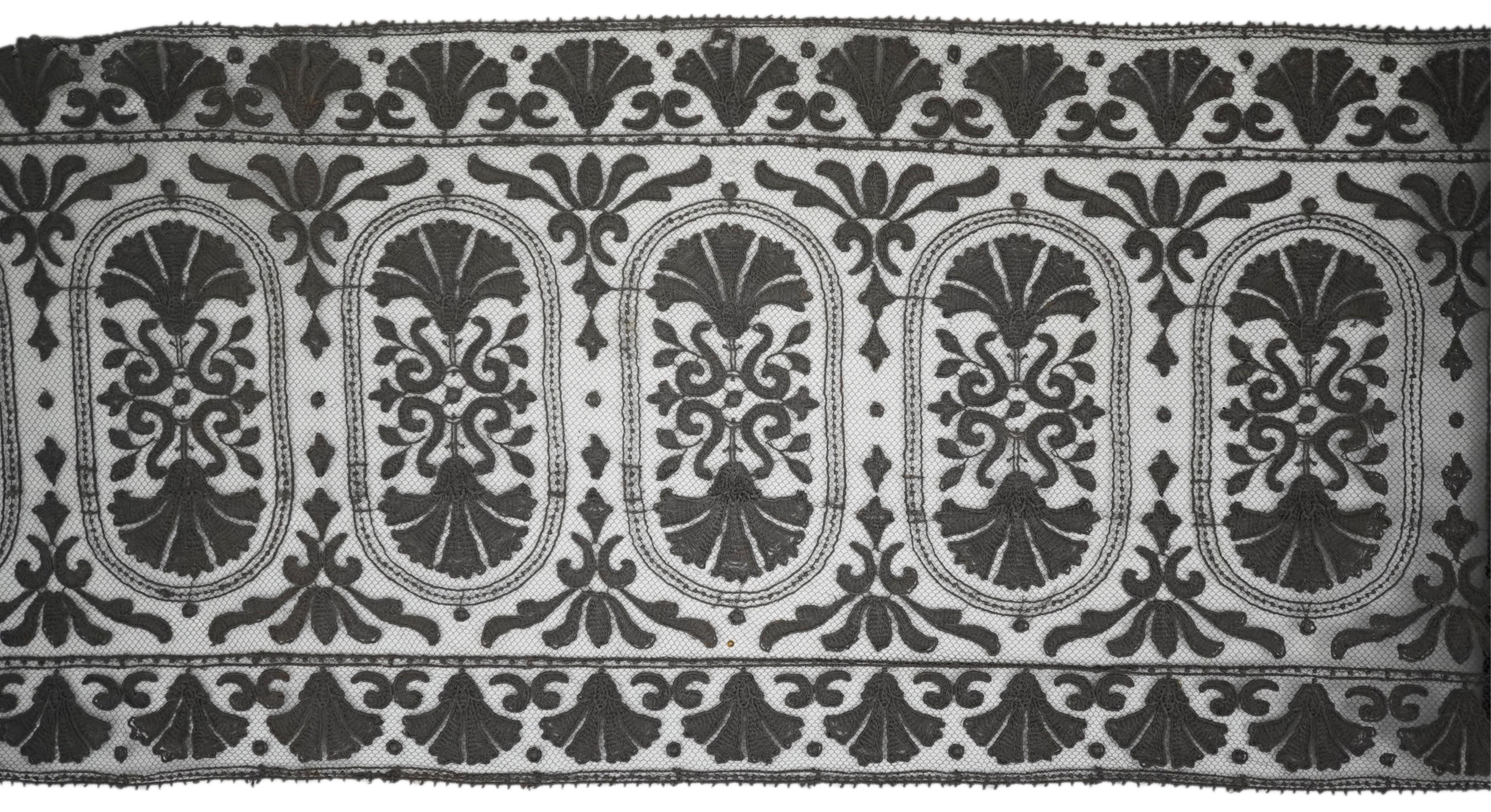 An unusual 19th century decorative length of charcoal grey machine furnishing lace, attributed to Christopher Dresser, together with a similar grey lace bonnet veil, both possibly Nottingham lace, furnishing lace 300cm j